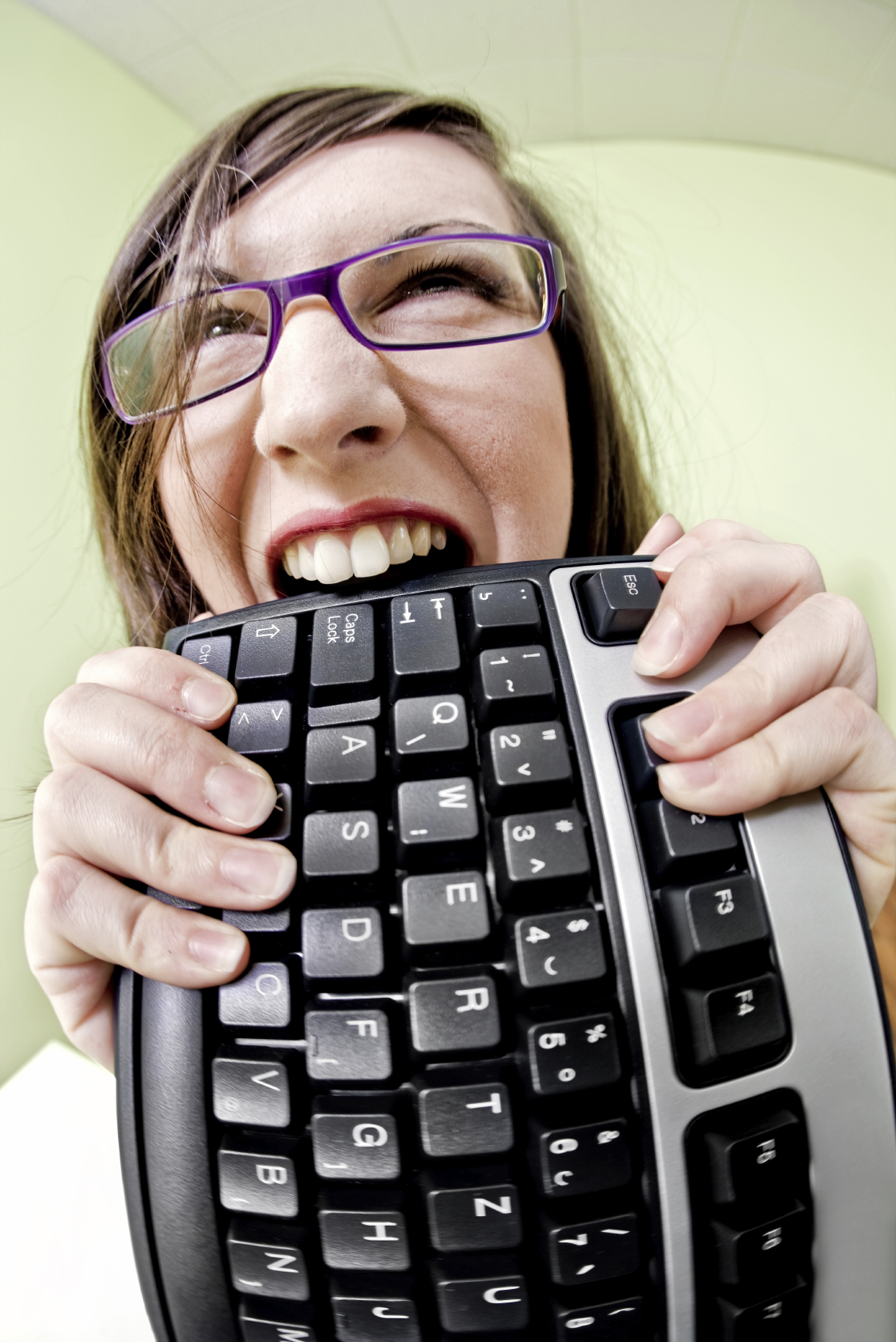 Frustrated computer user gnawing on keyboard.